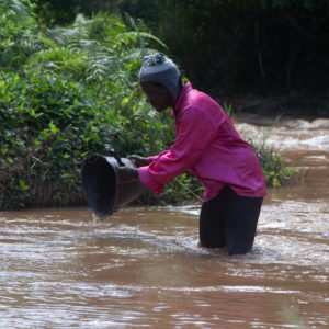 Woman gathering water from an unclean river