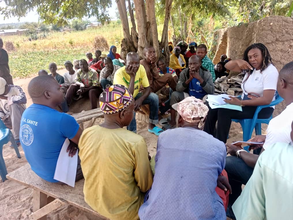 Community meeting on MDAs, Women sitting behind the tree, Oura Tada IDP Camp, Far North Region, Cameroon 